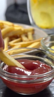 Ketçaplı bir tabak üzerinde kızarmış patates kızartması geniş açılı. Bir pipet ve bir kase patates dilimli cam bardak kola. Ekose piknik kağıdı üzerinde fast food öğle yemeği.. 