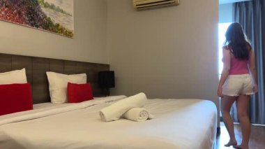 Genç kız cep telefonu otel odasına giriyor ve dinlenmek için yatağa uzanıyor. Uzun bir seyahatin ardından rahat bir iç mekan ışık atmosferi yaşam tarzı ve tatil rahatlama konsepti..