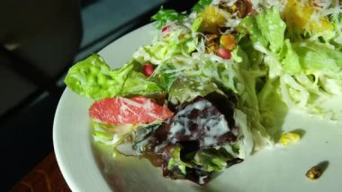 Dikey kesikli, tanınmayan erkek şefin beyaz seramik tabakta greyfurtlu lezzetli salata ve roka ile poz verişi. Yüksek kalite 4k görüntü