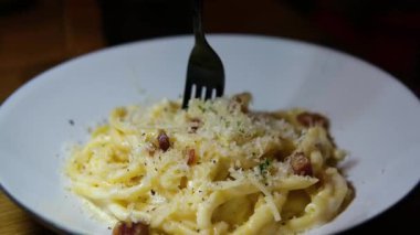 İtalyan makarnası pişirmek. Şampiyon Fetuçin ve fesleğenli krema. Şef makarna maşasıyla makarnayı karıştırır. Yakın plan, iştah açıcı yemek. Yüksek kalite 4k görüntü
