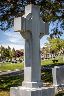 A large Celtic religious cross-shaped headstone at a cemetery in the day
