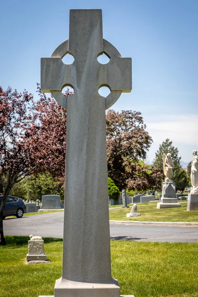 A large Celtic religious cross-shaped headstone at a cemetery in the day