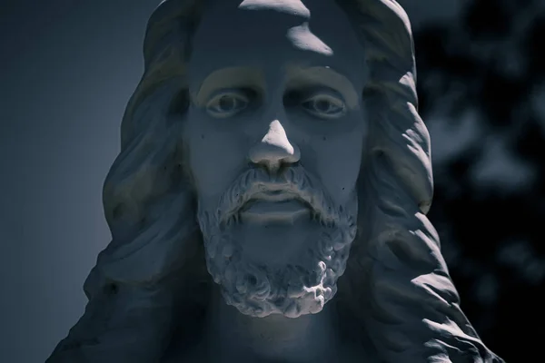 Close up of Jesus Christs Face on a stone grave marker at a cemetery