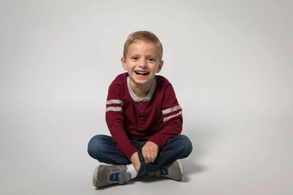 Mały Chłopiec Siedzący Śmiejący Się Przed Kamerą — Zdjęcie stockowe