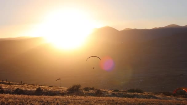 パラグライダーのシルエット山の夕日に向かって飛ぶ — ストック動画