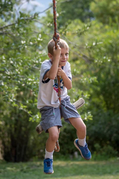 Boy Swinging on Rope Swing at Park