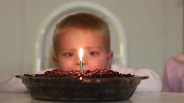 Kızdan önce mumu söndürmeye çalışan bir oğlan.