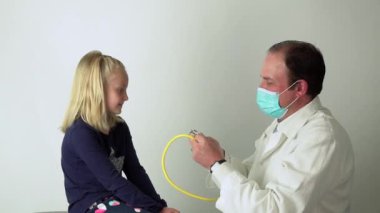 Doktor steteskop kullanarak küçük tatlı kızın kalbini dinlemesine izin veriyor.