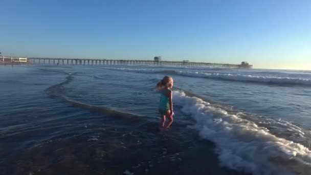 夕日で海の波を再生する女の子 — ストック動画