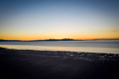 A Beach at a lake with a colorful sunset in the background high angle