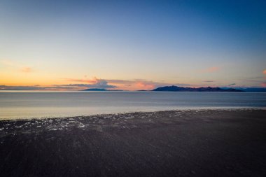 A Beach at a lake with a colorful sunset in the background high angle