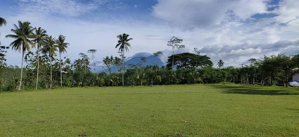 Doğu Cava 'da, Malang' daki Gunung Kawi Vadisi 'nde kale direkleri ve bitkilerle dolu bir futbol sahası. Hindistan cevizi ağaçları, palmiye ağaçları, sengon ağaçları, güzel manzara.