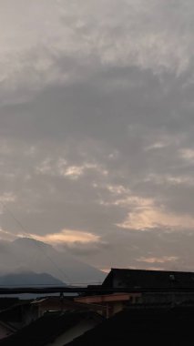 Evlerin çatıları olan gri gökyüzünün manzarası.