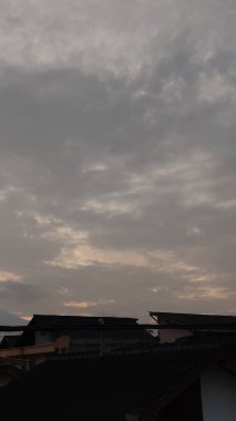 Evlerin çatıları olan gri gökyüzünün manzarası.