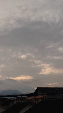 Evlerin çatıları olan gri gökyüzünün manzarası.