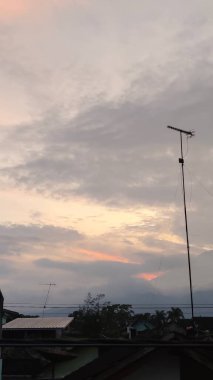 Evlerin ve antenlerin çatıları olan gri gökyüzünün manzarası