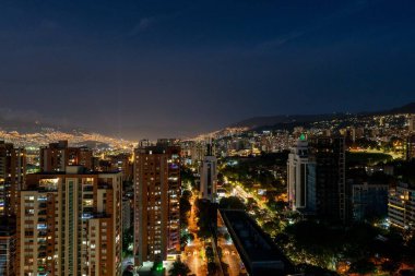 Medellin, Antioquia, Kolombiya. 21 Aralık 2020: El Poblado 'daki binalarla gece kent manzarası.