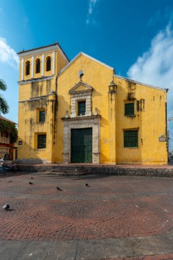 Cartagena, Bolivar, Kolombiya. 15 Mart 2023: Mavi gökyüzü ile park ve üçlü kilise.