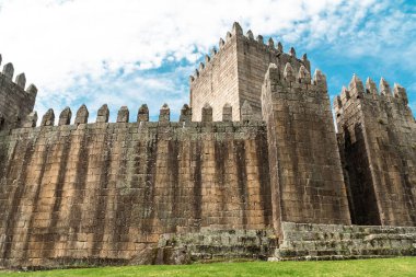 Guimaraes, Portekiz. 14 Nisan 2022: Mavi gökyüzü ile Guimares Kalesi 'nin duvarları ve yapıları.