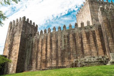 Guimaraes, Portekiz. 14 Nisan 2022: Mavi gökyüzü ile Guimares Kalesi 'nin duvarları ve yapıları.