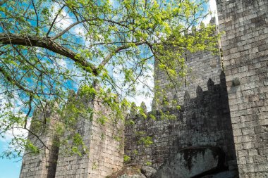 Guimaraes, Portekiz. 14 Nisan 2022: Mavi gökyüzü ile Guimares Kalesi 'nin duvarları ve yapıları.