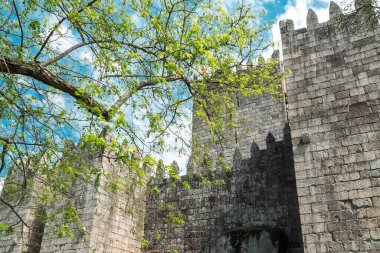 Guimaraes, Portekiz. 14 Nisan 2022: Mavi gökyüzü ile Guimares Kalesi 'nin duvarları ve yapıları.