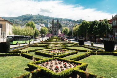 Guimaraes, Portekiz. 14 Nisan 2022: Mavi gökyüzü ve bahçeli Largo da Oliveira.