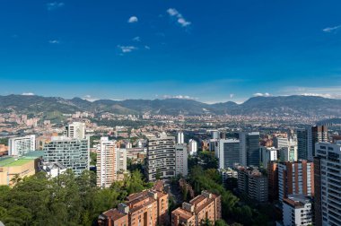Medellin, Antioquia, Kolombiya. 3 Mayıs 2023: Şehirdeki binalar ve mavi gökyüzüyle manzara.