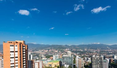 Medellin, Antioquia, Kolombiya. 3 Mayıs 2023: Şehirdeki binalar ve mavi gökyüzüyle manzara.