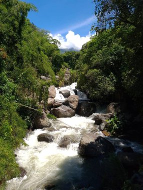 Mavi gökyüzü ile Cartama nehrinin manzarası. Nehirdeki taşlar. Tamesis, Antioquia, Kolombiya. 