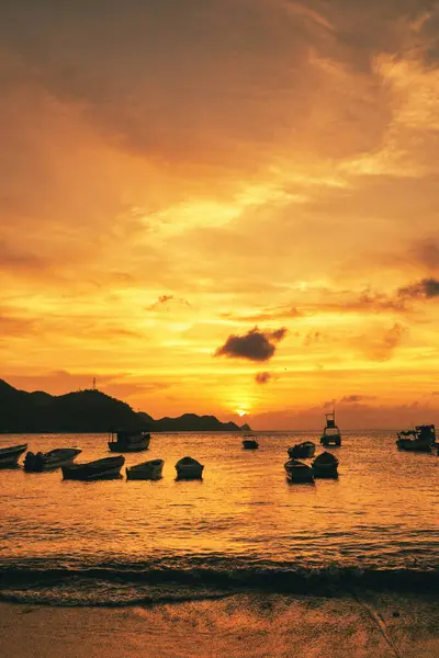 Denizde gün batımının ve kıyıda teknelerin olduğu manzara. Taganga Sahili. Santa Marta, Kolombiya. 