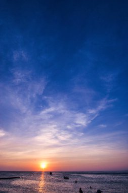 Sahildeki manzara, renkli günbatımı ve deniz kıyısındaki insanlar..