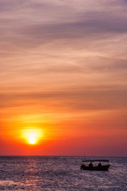 Sahildeki manzara, renkli günbatımı ve deniz kıyısındaki insanlar..