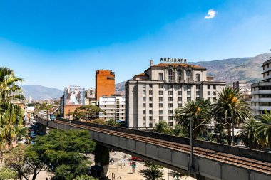Medellin, Antioquia, Kolombiya. 17 Ocak 2024: Mavi gökyüzü ile Nutibara Oteli ve Medellin metro rayları.