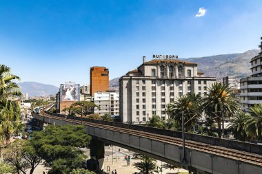Medellin, Antioquia, Kolombiya. 17 Ocak 2024: Mavi gökyüzü ile Nutibara Oteli ve Medellin metro rayları.