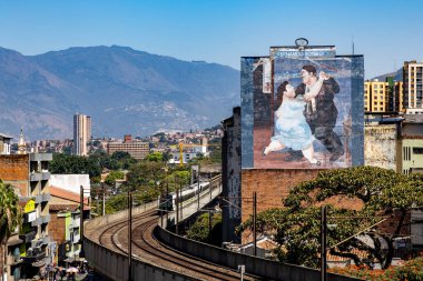 Medellin, Antioquia, Kolombiya. 17 Ocak 2024: Fernando Botero 'nun resmi ve Medellin metrosunun mavi gökyüzü manzarası.