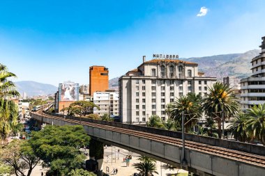 Medellin, Antioquia, Kolombiya. 17 Ocak 2024: Mavi gökyüzü ile Nutibara Oteli ve Medellin metro rayları.