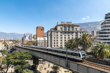 Medellin, Antioquia, Kolombiya. 17 Ocak 2024: Mavi gökyüzü ile Nutibara Oteli ve Medellin metro rayları.