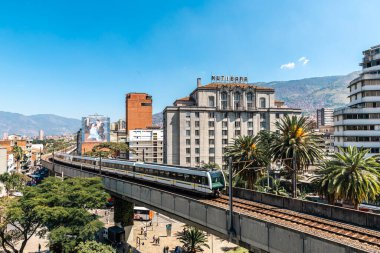 Medellin, Antioquia, Kolombiya. 17 Ocak 2024: Mavi gökyüzü ile Nutibara Oteli ve Medellin metro rayları.