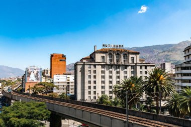 Medellin, Antioquia, Kolombiya. 17 Ocak 2024: Mavi gökyüzü ile Nutibara Oteli ve Medellin metro rayları.