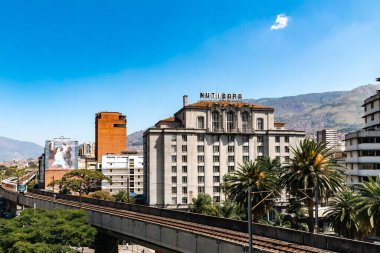 Medellin, Antioquia, Kolombiya. 17 Ocak 2024: Mavi gökyüzü ile Nutibara Oteli ve Medellin metro rayları.
