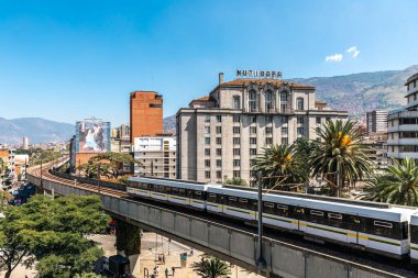 Medellin, Antioquia, Kolombiya. 17 Ocak 2024: Mavi gökyüzü ile Nutibara Oteli ve Medellin metro rayları.