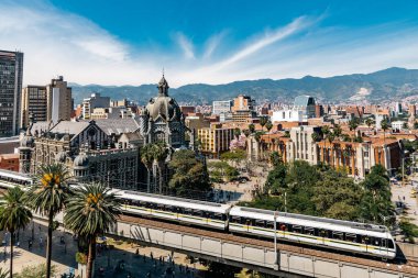 Medellin, Antioquia, Kolombiya. 17 Ocak 2024: Fernando Botero 'nun resmi ve Medellin metrosunun mavi gökyüzü manzarası.