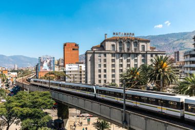 Medellin, Antioquia, Kolombiya. 17 Ocak 2024: Mavi gökyüzü ile Nutibara Oteli ve Medellin metro rayları.
