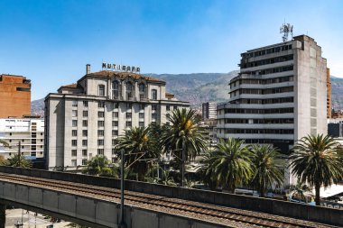 Medellin, Antioquia, Kolombiya. 17 Ocak 2024: Mavi gökyüzü ile Nutibara Oteli ve Medellin metro rayları.