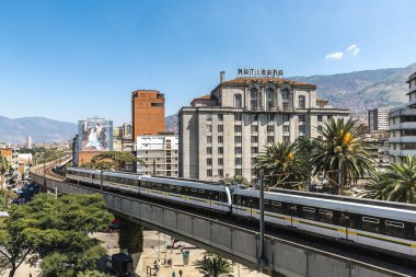 Medellin, Antioquia, Kolombiya. 17 Ocak 2024: Mavi gökyüzü ile Nutibara Oteli ve Medellin metro rayları.