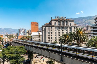 Medellin, Antioquia, Kolombiya. 17 Ocak 2024: Mavi gökyüzü ile Nutibara Oteli ve Medellin metro rayları.