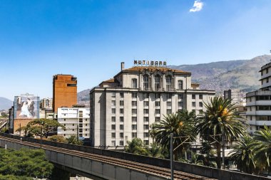 Medellin, Antioquia, Kolombiya. 17 Ocak 2024: Mavi gökyüzü ile Nutibara Oteli ve Medellin metro rayları.