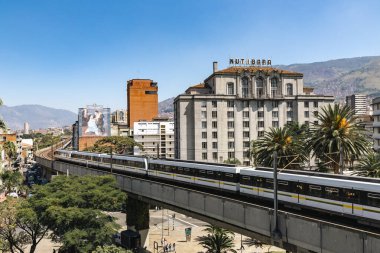 Medellin, Antioquia, Kolombiya. 17 Ocak 2024: Mavi gökyüzü ile Nutibara Oteli ve Medellin metro rayları.