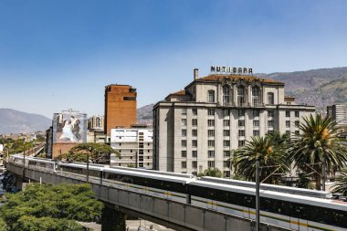 Medellin, Antioquia, Kolombiya. 17 Ocak 2024: Mavi gökyüzü ile Nutibara Oteli ve Medellin metro rayları.